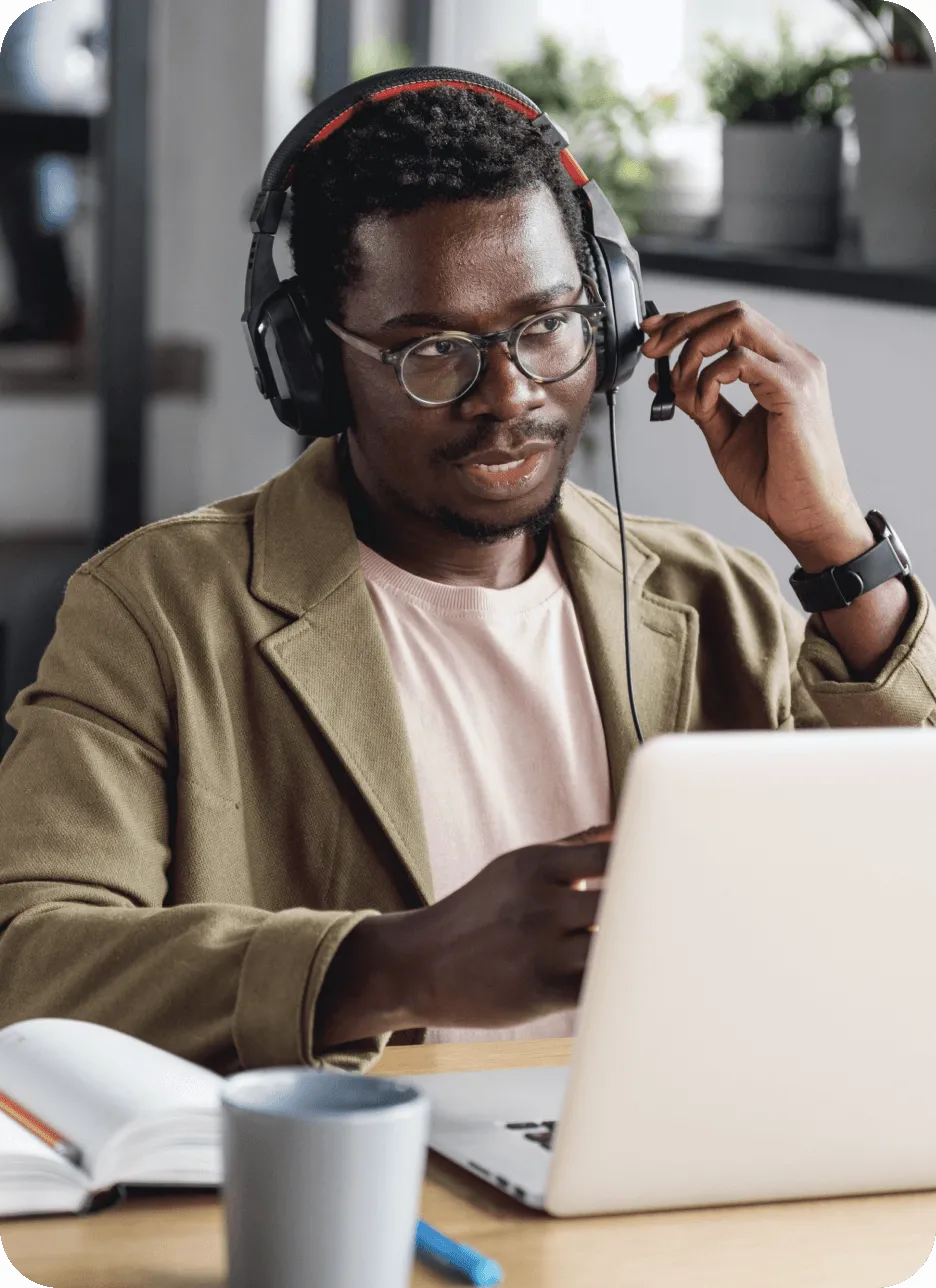 A male worker with headphones on in front of a laptop