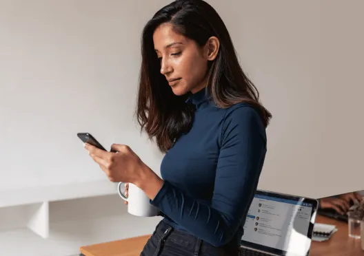 A woman using her phone while having a cup of coffee