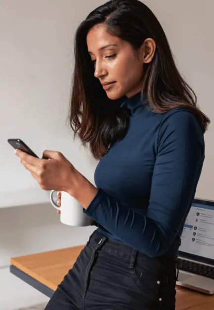 A woman using her phone while having a cup of coffee