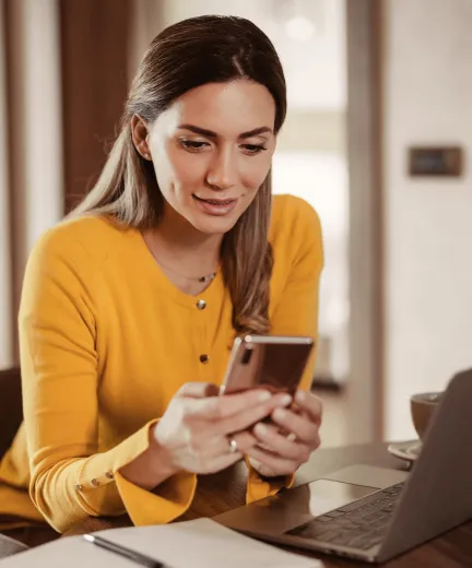 A woman using the RingCentral app on her cellphone and laptop