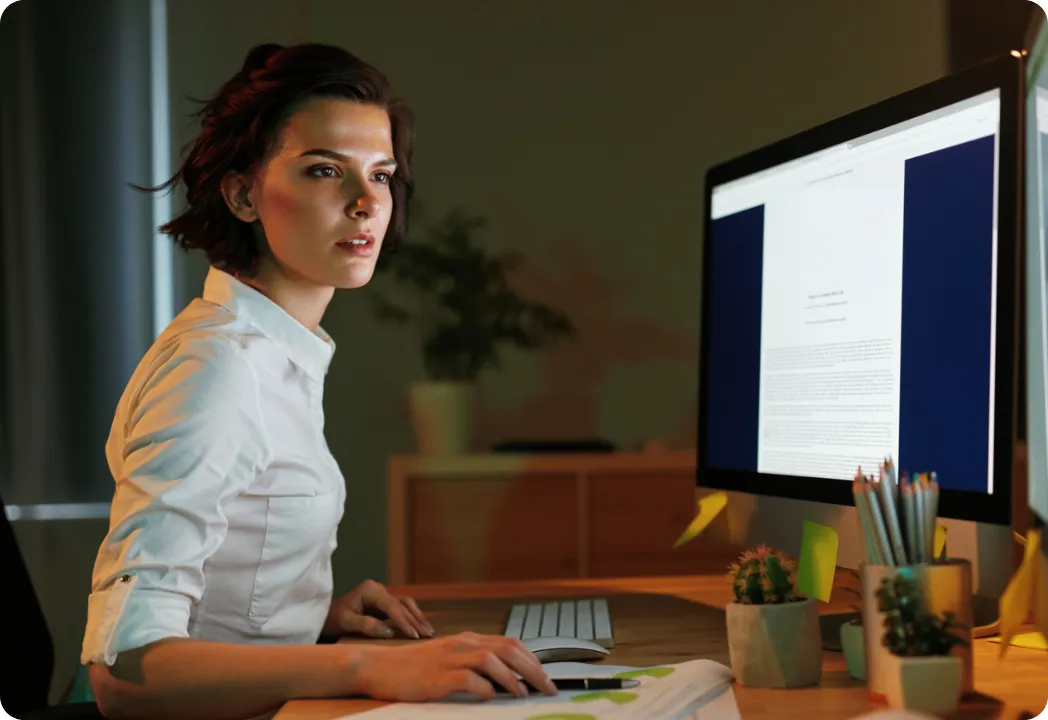 A woman reviews a document on her monitor