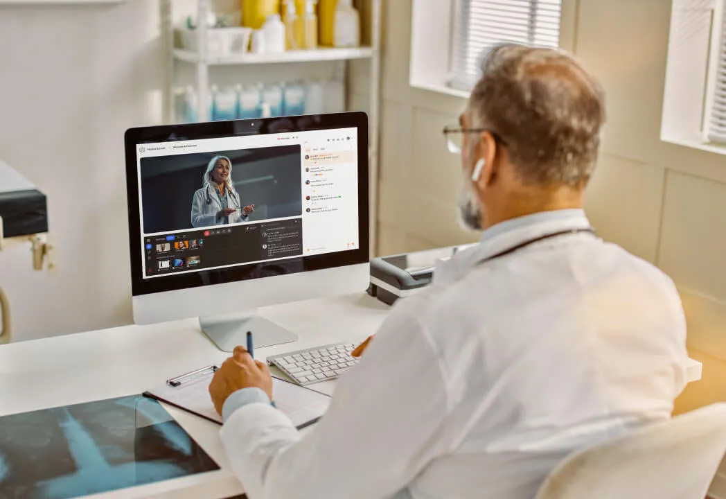 A male medical professional sitting at a desk attends a virtual event